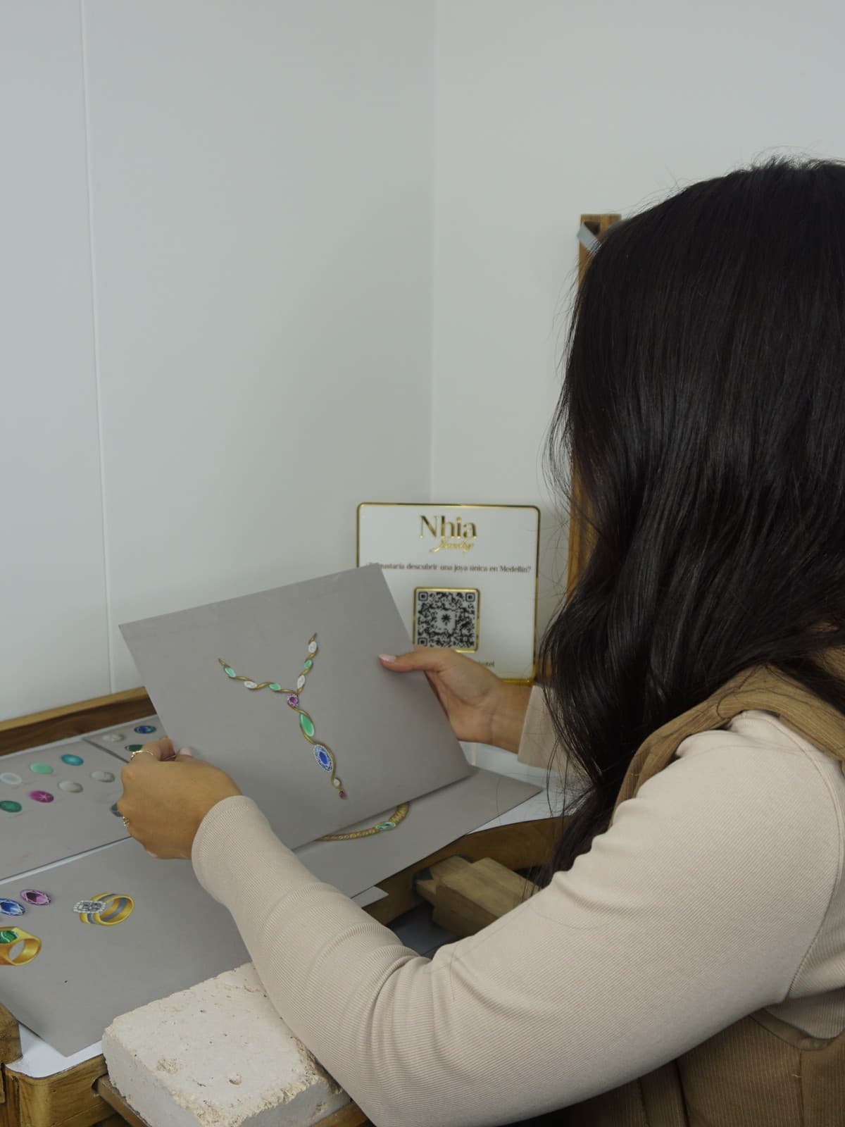 Helen revisando un boceto en su escritorio, con anillos Nhia sobre la mesa
